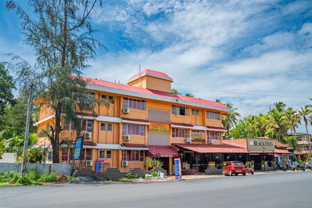 Side view of Hotel Colva Plaza with palm trees